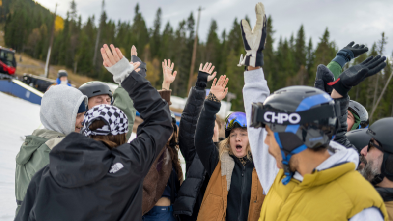 En grupp med åkare och ledare som sträcker upp en hand i luften.