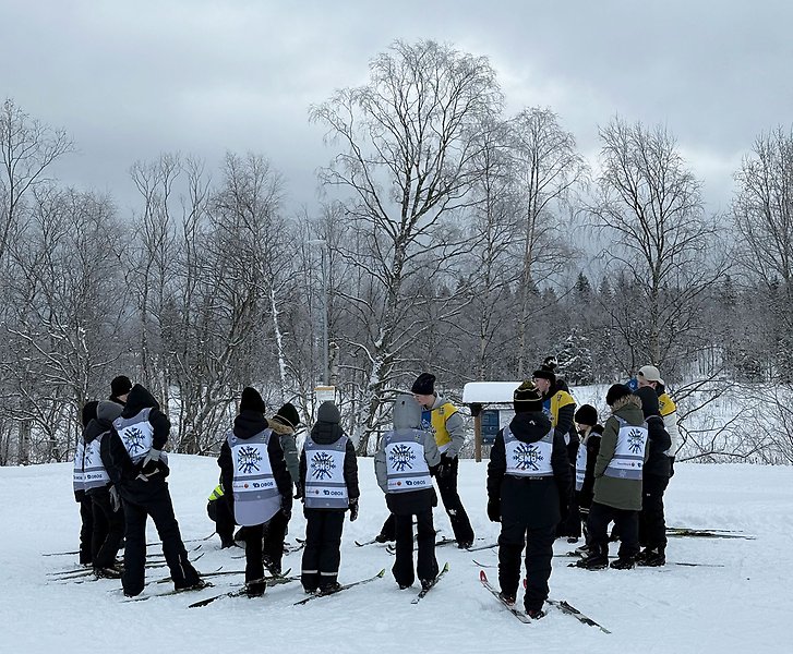 Fjärdklassare står i en ring och lyssnar på ledare.